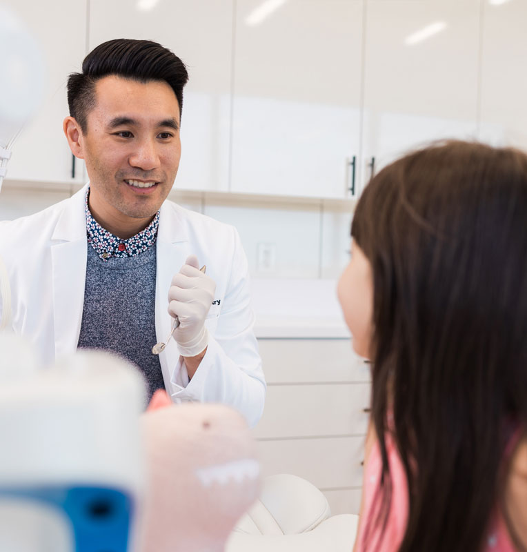 Pediatric dentist consulting with a young patient in a bright, welcoming dental office, emphasizing compassionate care for children in Huntington Beach.