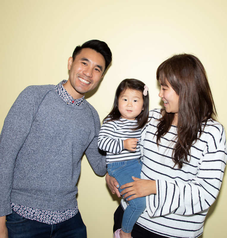 Smiling family with a young girl in striped shirts, showcasing a friendly and welcoming atmosphere, reflecting the Kind Smiles pediatric dental care focus on comfort and kindness for children.