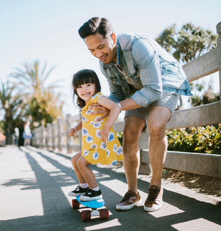 Father helping his daughter ride a skateboard