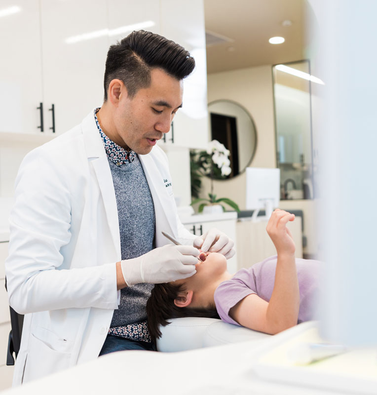 Pediatric dentist providing gentle dental care to a child in a modern dental office at KIND SMILES, near Lake Forest.