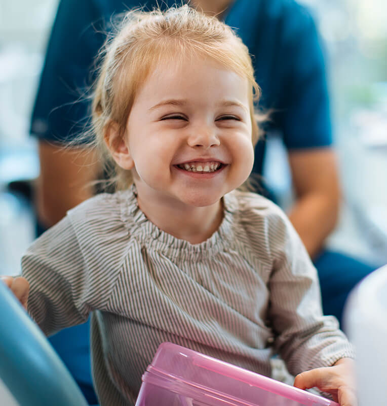Smiling young girl in a dental office, showcasing a positive experience with pediatric laser dentistry at Kind Smiles Orthodontics.