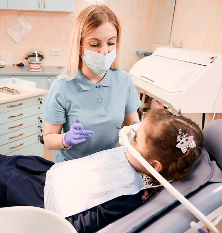Dental professional administering nitrous oxide sedation to a young child during a dental procedure, ensuring a calm and safe experience at KIND SMILES Pediatric Dentistry.